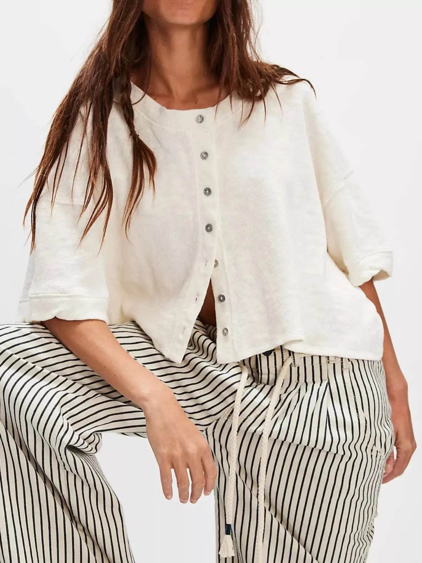 Women's button-front half sleeve cardigan in off-white with black and white striped pants.