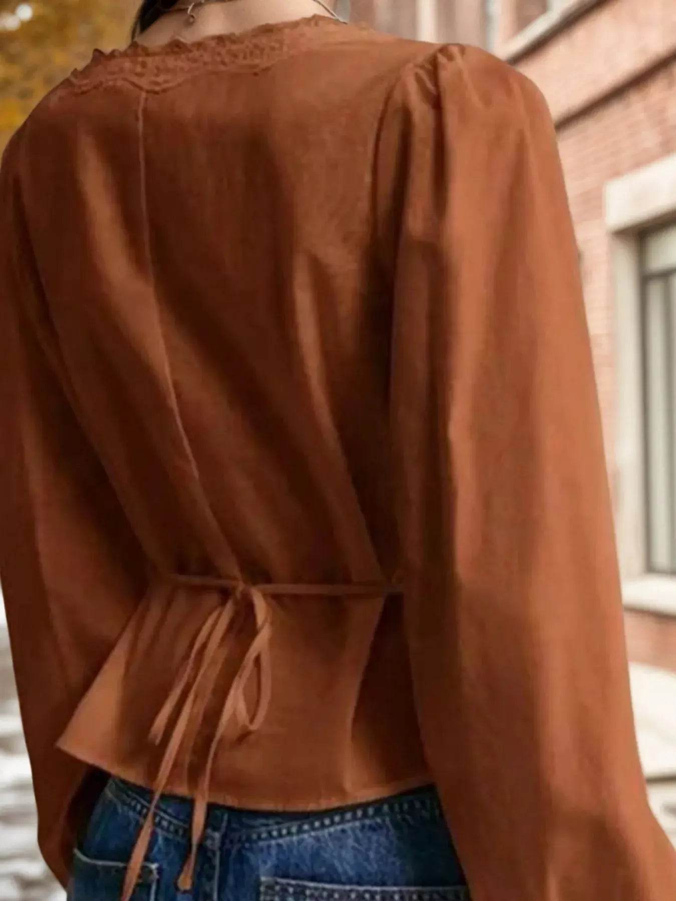 Brown lace detail balloon sleeve blouse with a tie-back waist, worn with blue jeans.