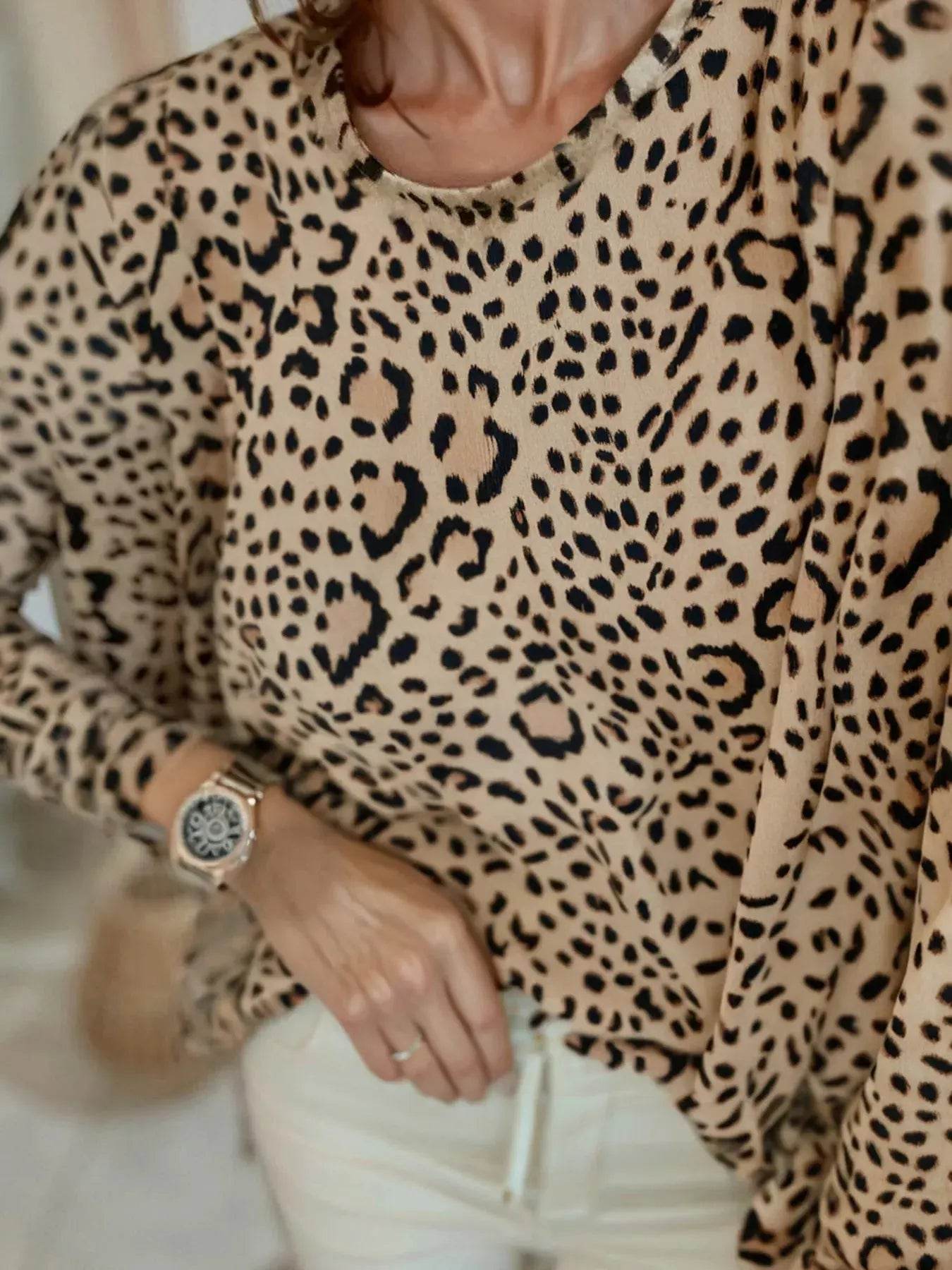 A woman wears a leopard print long-sleeve t-shirt with white pants and a watch.