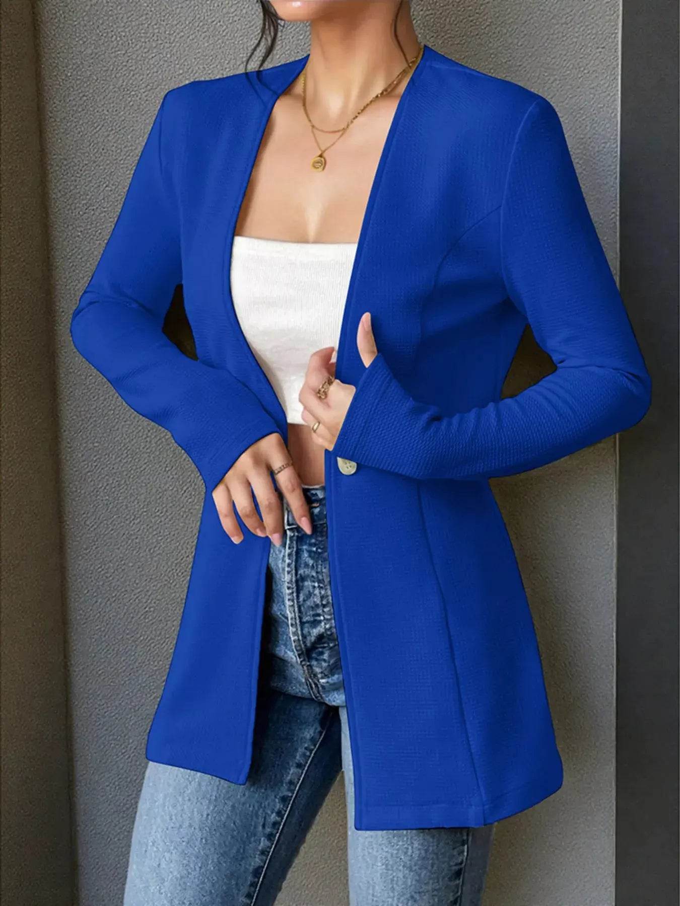 A woman wears a royal blue single-button long-sleeve blazer over a white crop top and jeans.