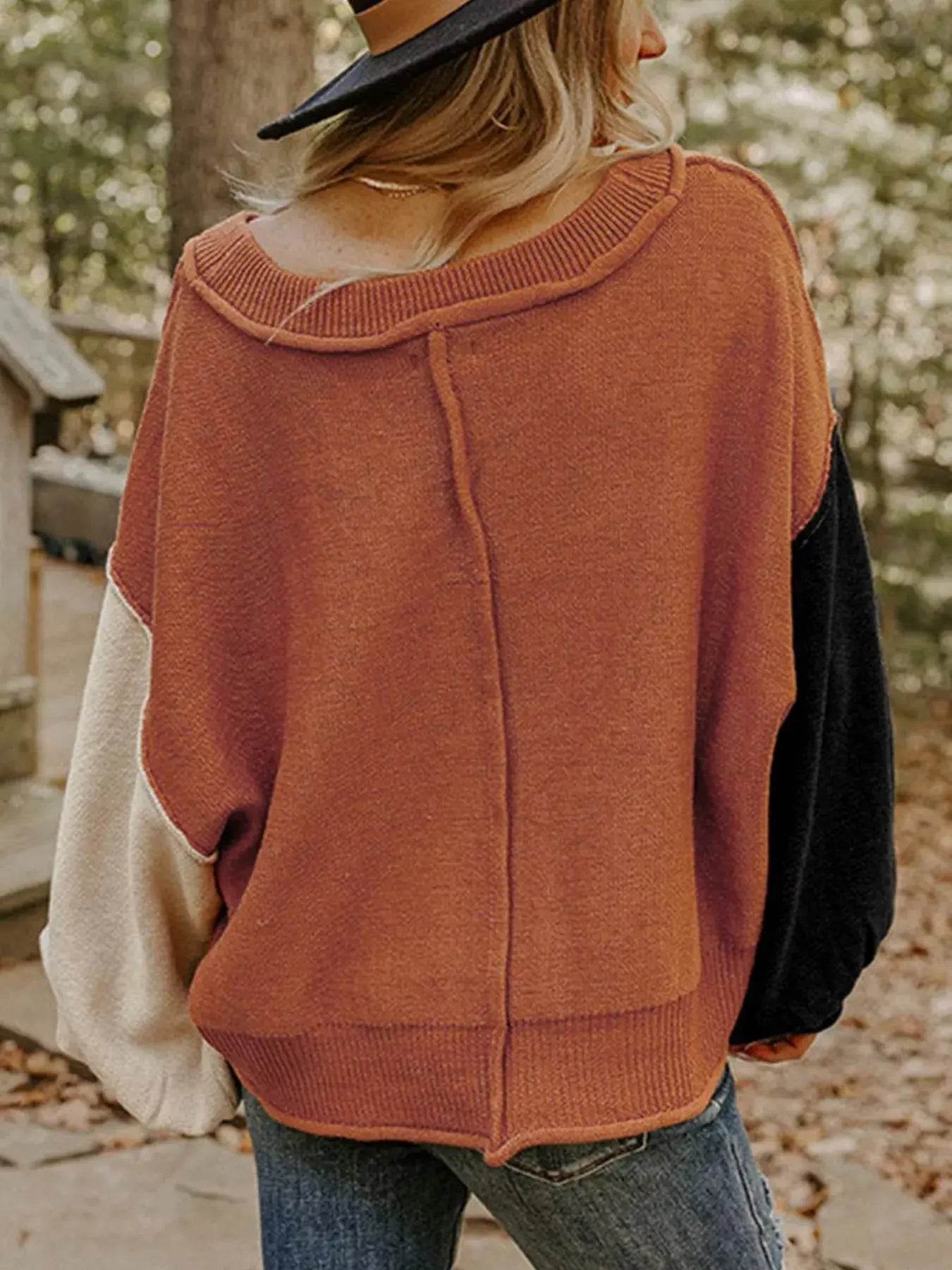 A woman from behind wears a ribbed hem long sleeve sweater with color block sleeves.