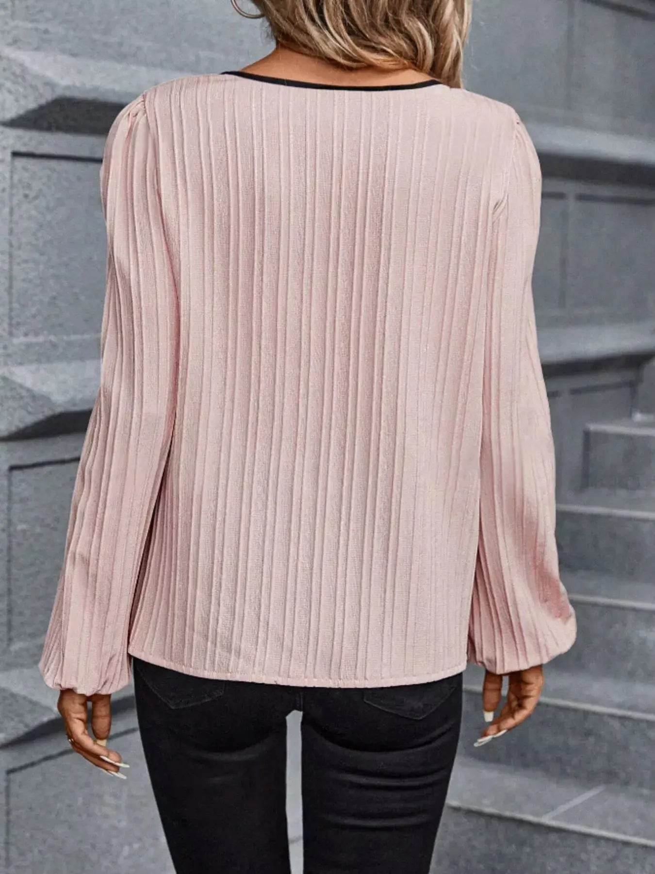 Pink textured long sleeve blouse with a notched neckline.