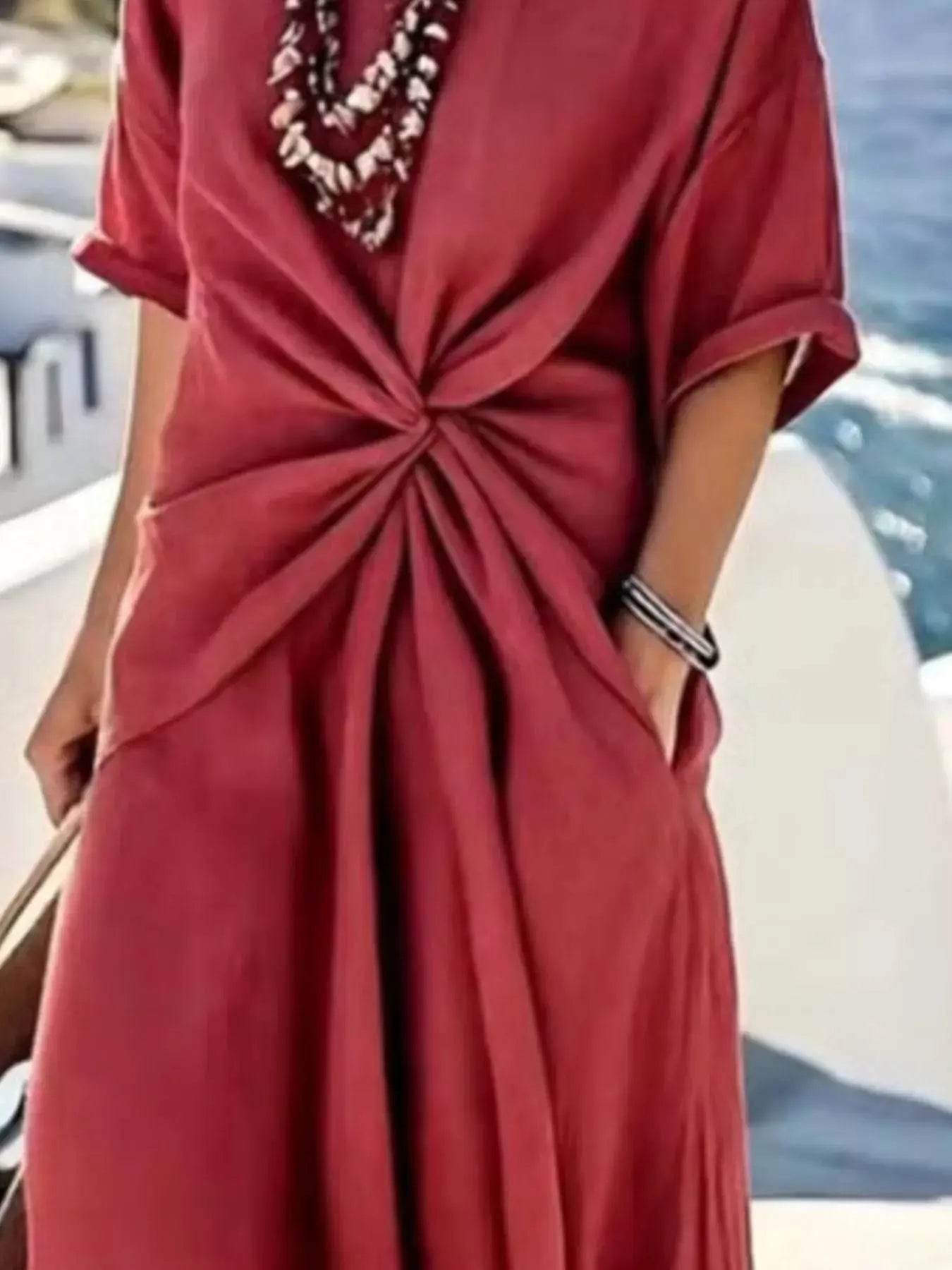 A woman wears a red twist-front, V-neck, half-sleeve maxi dress with pockets.