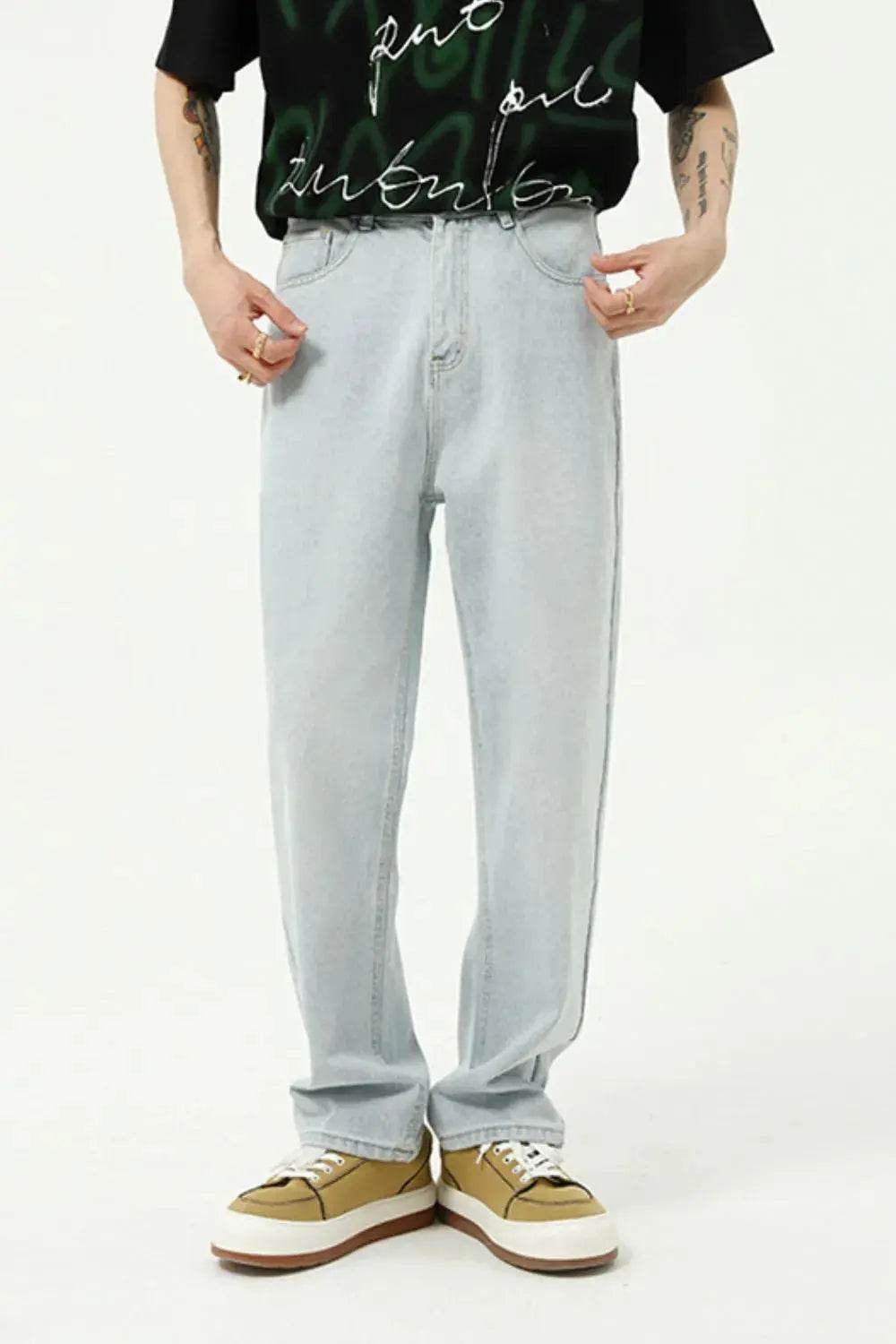 Men's light wash straight-leg jeans with a black graphic tee and tan sneakers.