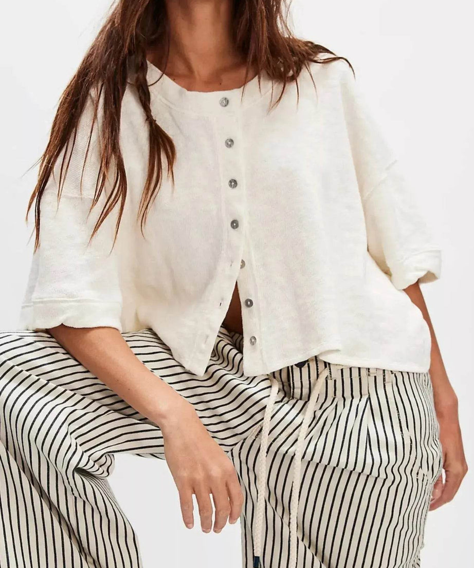 Women's button-front half sleeve cardigan in off-white with black and white striped pants.