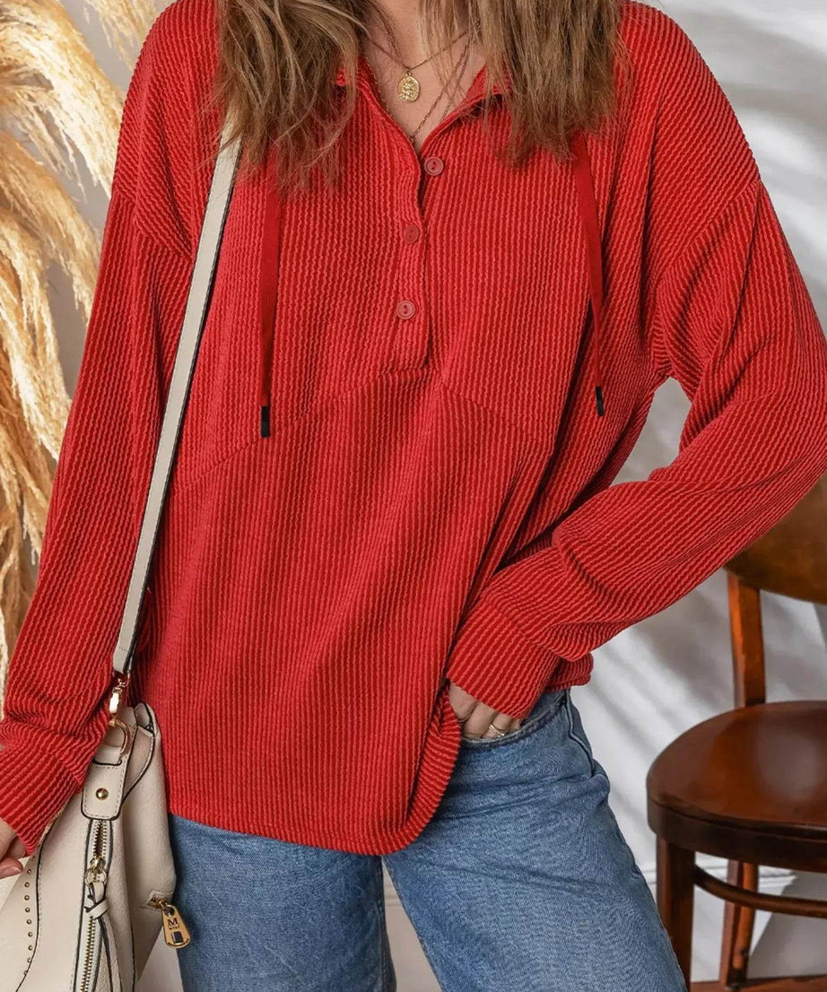 Red ribbed half-button collared drawstring top with long sleeves.
